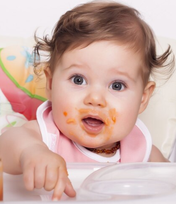 Infant eating mashed pumpkin